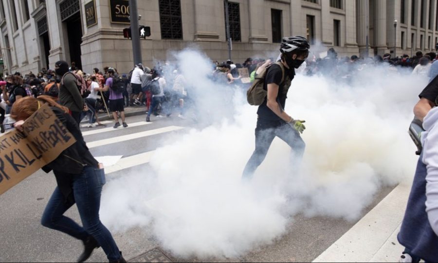 Protesters flee as tear gas canisters are released among the crowd.
