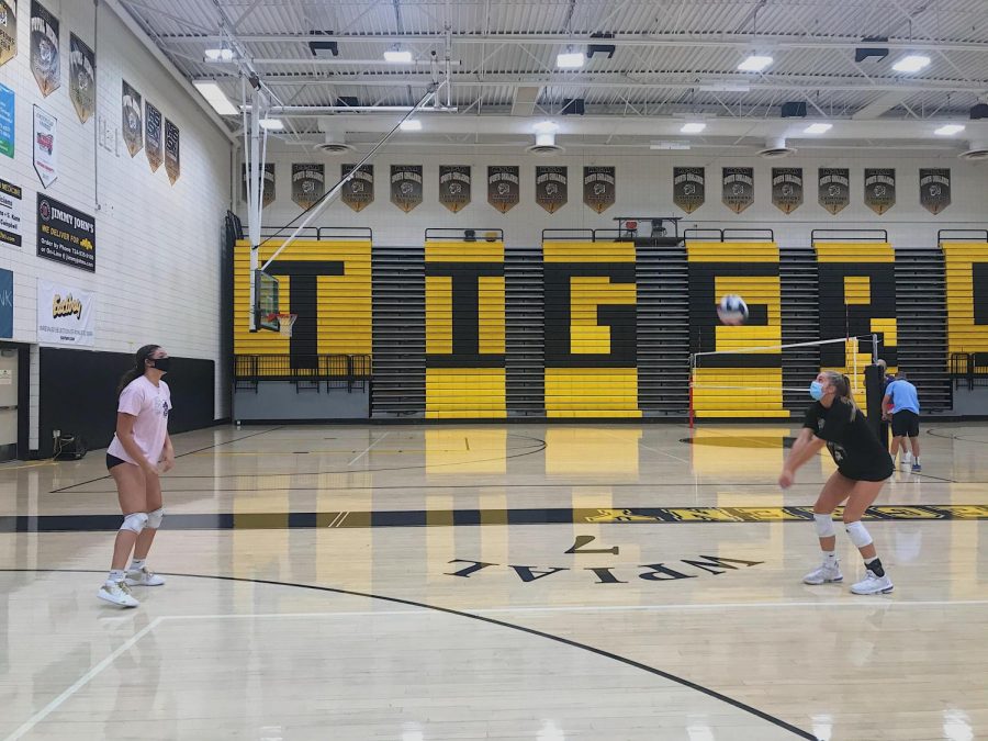 Jadyn Perkins and Mia Tuman pass the ball from a safe distance at a recent volleyball practice.