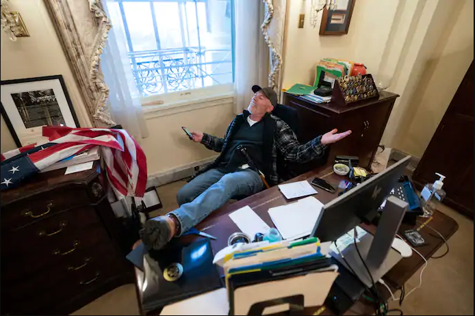 Richard Barnett from Arkansas sits at Speaker of the House Nancy Pelosis desk after the breach of Capitol Hill