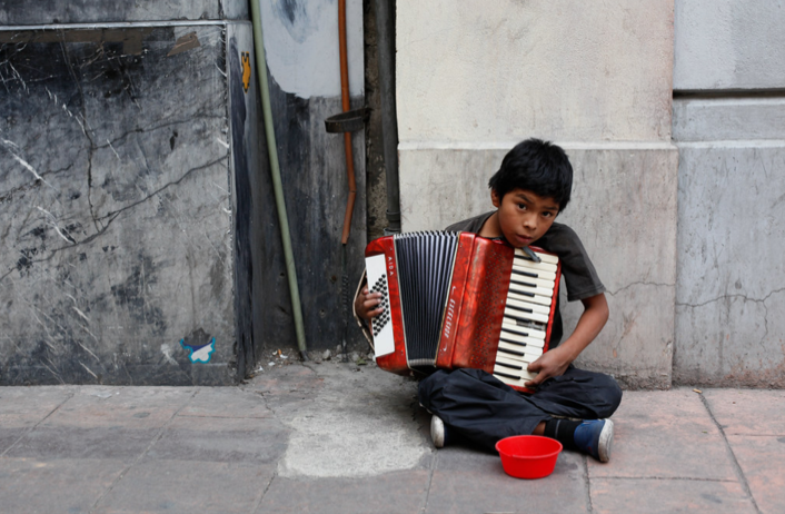 A young boy in the streets of Mexico City plays the accordion for spare change. 