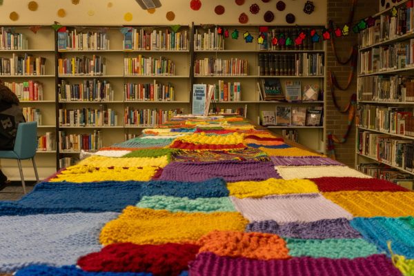 Pops of color hide underneath exhibits of books, and a rainbow of knitted webs of varying size and color hang above the shelves.