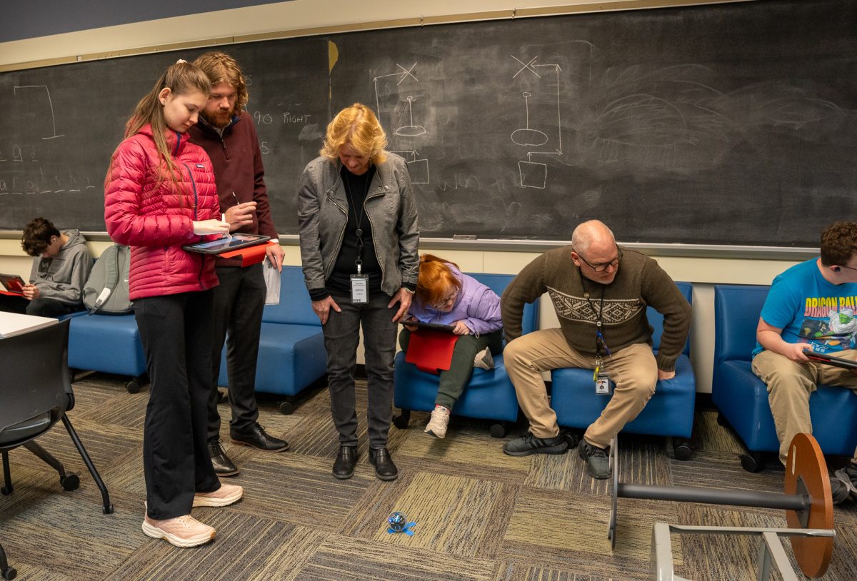 Mr. Graham, Ms. Brennan, and Mr. Mitts watch as Jessica Galbiati and Sara Whipkey display their Sphero's abilities.