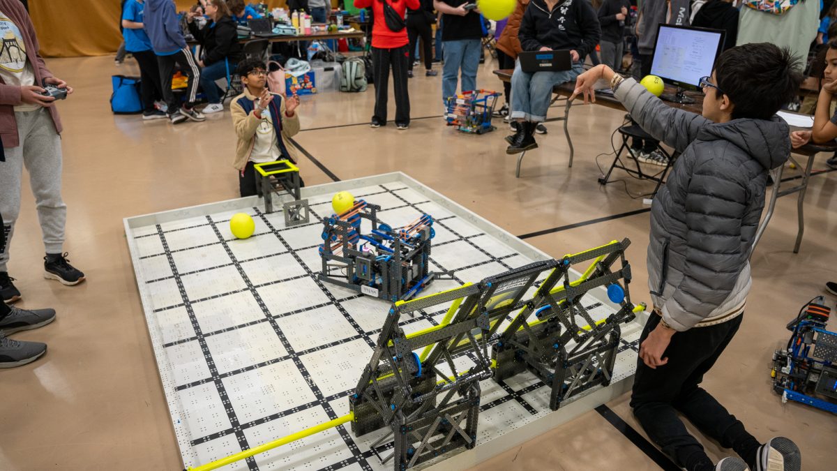 A middle school competition field where teams attempt to have their robots shoot balls into a hoop.