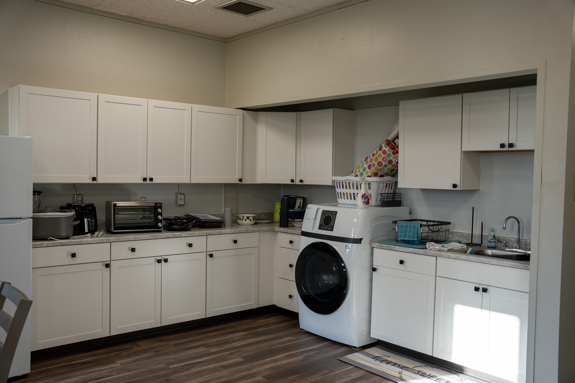 The kitchen area of the apartment, complete with a sink, fridge, and other appliances.